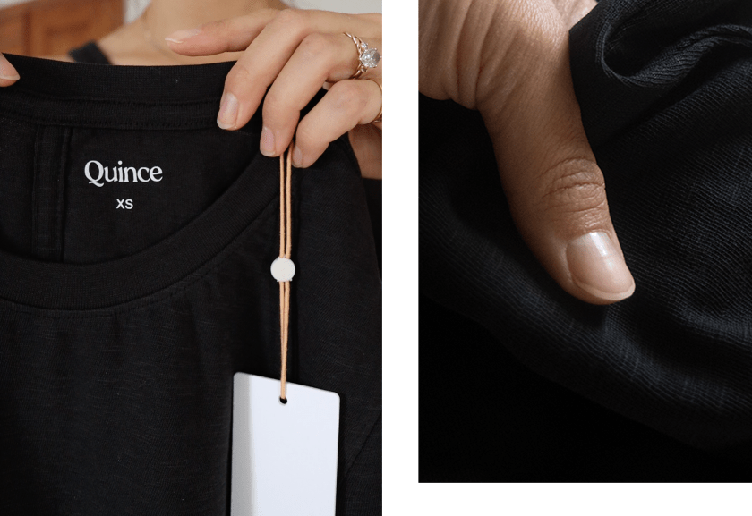 Close-up of a black Quince shirt with the label visible, held by a person.