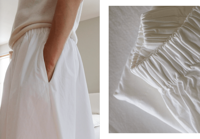 A model showcasing a Quince white poplin skirt with a side pocket, paired with a light top, emphasizing the fabric's quality.