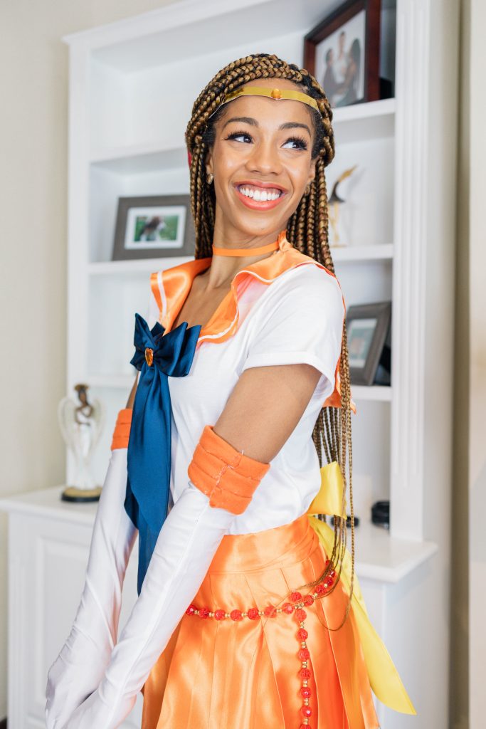 Black woman smiling wearing DIY Sailor Venus Costume for Halloween. Blonde Box Braids instead of hair/wig.