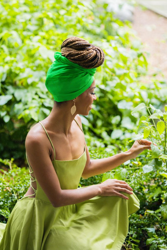 Black woman in Green Dress. Box Braids in Top Bun with Green headwrap. Halloween Inspiration