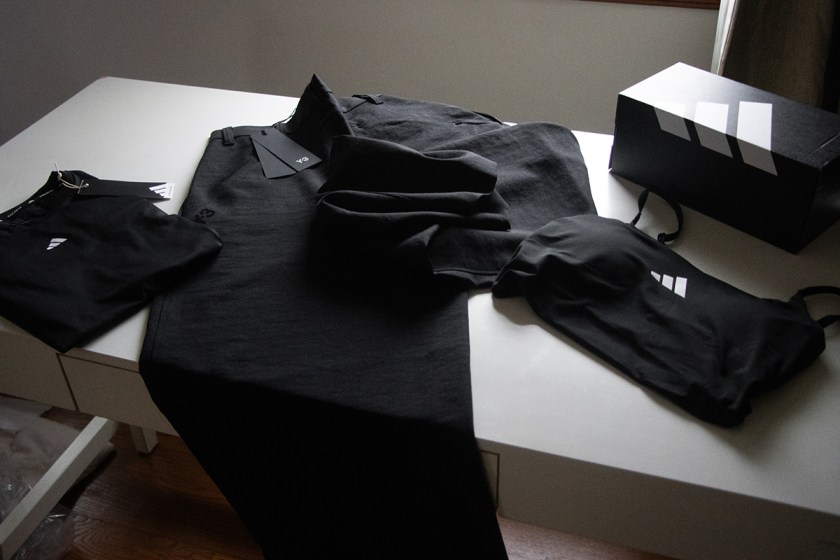 A collection of black yoga clothing, including a top, pants, and a bra, displayed on a table along with a branded adidas box.